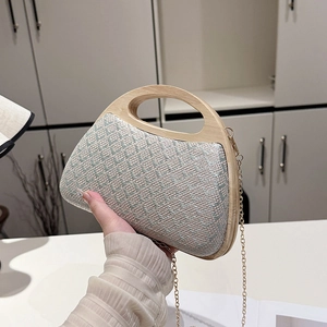 Blue and beige woven handbag with wooden handle and gold chain strap in minimalist setting