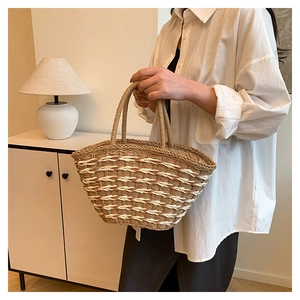 Detail of woven straw tote bag featuring brown trapezoidal pattern and sturdy handles