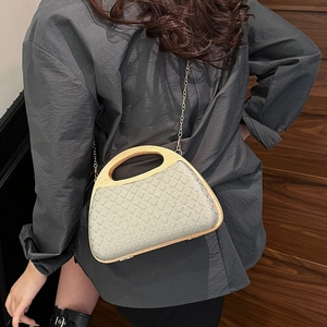 Straw handwoven crossbody bag with wooden handle and gold chain on wooden stairs