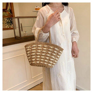 Close-up of a striped straw woven tote bag with curved handles for summer beach fashion