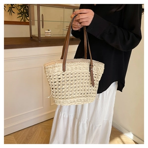 Détail du sac seau en paille tissée avec poignées en cuir et fermeture par cordon serrage