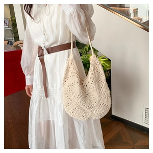 Detail of hand-crocheted beige hobo bag with hollow floral patterns for summer