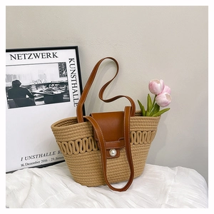 Detail of woven straw tote bag featuring leather flap and oversized pearl closure buckle