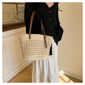 Détail du sac cabas en paille tressée avec poignées en cuir marron et texture tissée