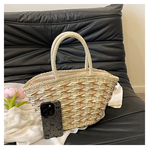 Detail view of woven straw tote bag texture and reinforced handles with flowers on the side