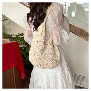 Detail of bohemian cream crochet shoulder bag with intricate floral knit pattern on model