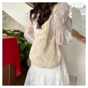 Detailed close-up of a beige crochet woven shoulder bag with intricate floral patterns