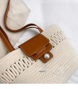 Detail of woven tote bag with brown leather flap, contrast stitching and pearl button