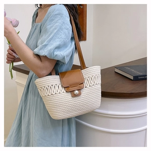 Close-up of woven bucket bag featuring elegant pearl buckle and brown leather flap