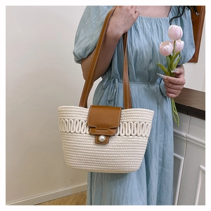 Detail of white woven bucket bag with brown leather strap and large pearl closure