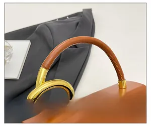 Detailed macro view of the golden twisted metal handle and brown leather on the saddle bag