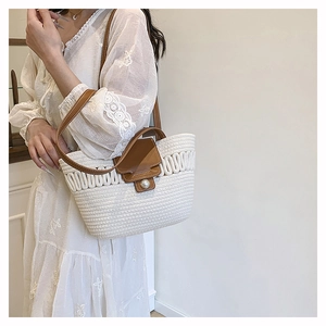 Detail view of straw woven tote with brown leather flap and large pearl closure