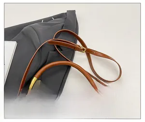 Detailed close-up of brown leather saddle bag featuring a unique curved gold metal handle