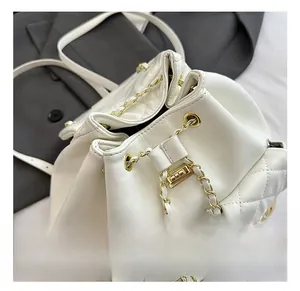 Detail view of white quilted bucket backpack with gold chain drawstring and hardware