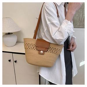 Detail of woven straw bucket bag with leather strap and large pearl closure detail