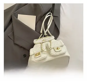 Detail of white quilted backpack with gold chain straps and turn-lock pockets