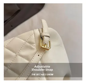 Detail of adjustable shoulder strap with gold buckle on cream quilted leather bag