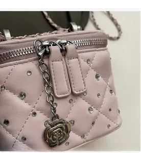 Detail of pink quilted leather mini bag with silver double zippers and rose charm