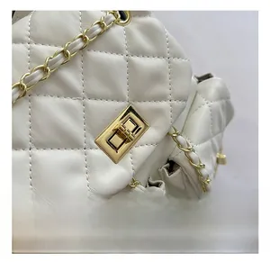 Detail of white quilted leather bag showing gold hardware lock and chain strap