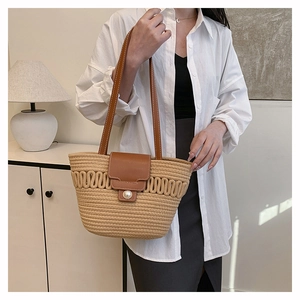 Detail of woven tote bag featuring pearl buckle and brown leather flap for 2025 fashion