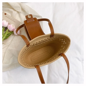 Top view of woven straw tote bag with brown leather clasp and spacious interior detail
