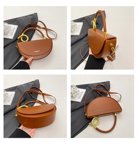 Detail view of a brown saddle bag featuring a gold metal handle and leather shoulder strap