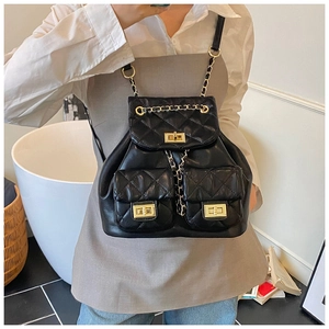 Detail of quilted black leather backpack featuring gold twist-lock and chain straps