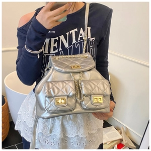 Detail of silver quilted backpack featuring gold chains and front pockets for women