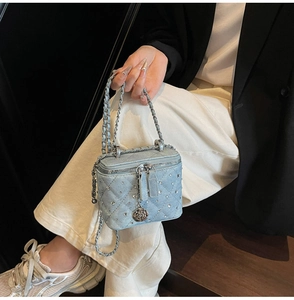 Detail of light blue denim quilted bag with rhinestones and silver rose zipper charms