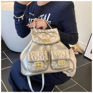 Detail of silver quilted backpack with gold twist-locks and woven metal chain straps