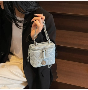 Close-up of light blue quilted mini bag with crystal studs and rose charm detail