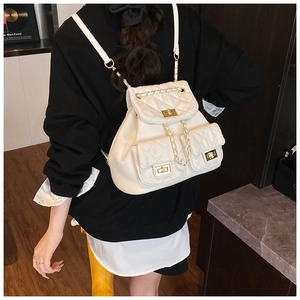 Close-up of white quilted mini backpack featuring gold twist locks and chain straps