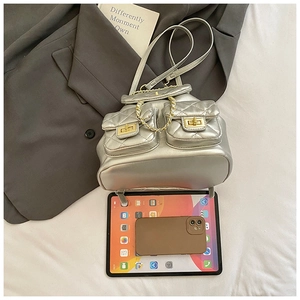 Quilted silver backpack showing storage capacity with a tablet and smartphone next to it