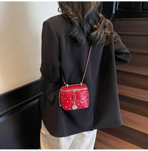 Detail of red quilted mini vanity bag with silver studs and rose charm on chain strap