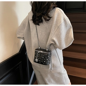 Detail of a mini black quilted box bag with sparkling crystals and camellia charm