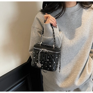 Close-up of black quilted mini box bag with sparkling stud accents and rose charm detail