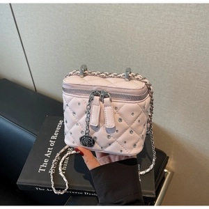 Detail of pink quilted vanity bag featuring rhinestone studs and camellia pendant