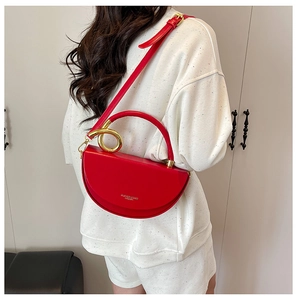Detail of red crescent leather bag with gold circular handle and shoulder strap