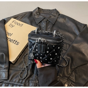 Close-up of black quilted mini vanity bag with crystal studs and rose charm detail