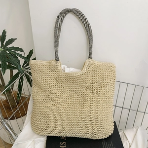 Beige woven straw tote bag with black and white striped handles and textured hollow design