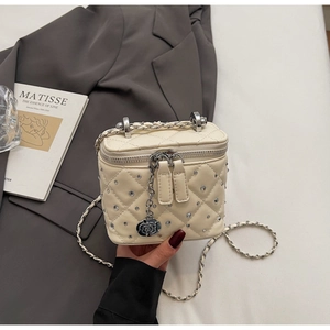 Detail of beige quilted mini bag with crystal studs and camellia charm pendant
