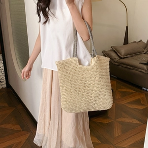 Handwoven straw tote bag with black and white striped handles for summer vacation style