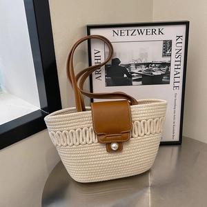 Minimalist woven shoulder bag with pearl clasp and leather trim on metallic table