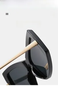 Détail de lunettes de soleil carrées noires avec branches en métal doré légères