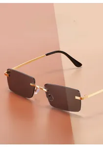 Détail de lunettes de soleil rectangulaires sans monture avec verres gris et branches dorées