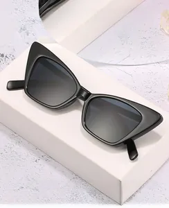 Detail shot of black cat-eye sunglasses on a white geometric stand with frame specs