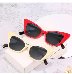 Close-up of retro cat-eye sunglasses in red and beige on a geometric white display