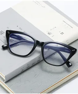 Close-up of shiny black cat-eye glasses frame with blue light blocking lenses on books