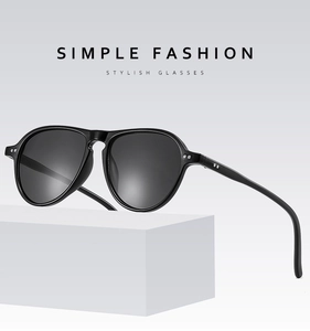 Classic black full-rim sunglasses with gray lenses displayed on a geometric base