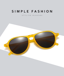 Detailed close-up of yellow transparent pilot sunglasses with dark grey lenses on white background